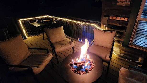 A deck with a fire pit, outdoor seating, and string lights. - Come to the Hideout! Hot Tub, Fire Pits & Views! (Woodland Park)