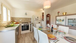 Eine moderne Küche mit Essbereich, ausgestattet mit Backofen, Kühlschrank und einem Esstisch für sechs Personen.