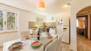 Ein Essbereich mit einem Tisch für vier Personen, eine Küche mit einem Kühlschrank mit der Aufschrift "The Café" und Blick auf das angrenzende Badezimmer.