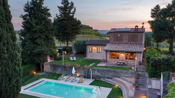A residential property with a swimming pool, a patio with outdoor seating, and a house with a tiled roof.