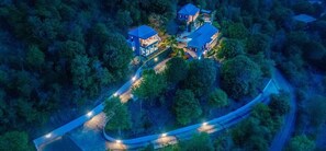 An aerial view of a residential area with multiple houses surrounded by dense forest.