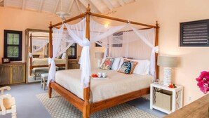 A four-poster bed with a canopy, a bedside table with a lamp, and a vase with flowers.