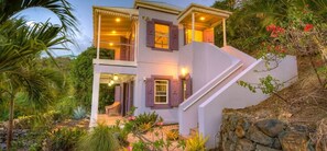 A two-story house with a staircase, a balcony, and a garden.