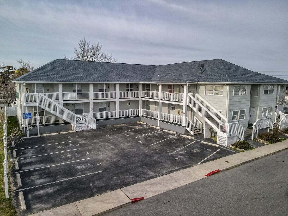 Un motel con un estacionamiento central, varios balcones y una estructura de dos pisos.
