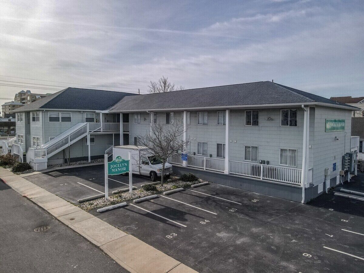 Ein Motel mit Parkplatz, Treppe und einem Schild mit der Aufschrift 'Jocelyn Manor'.