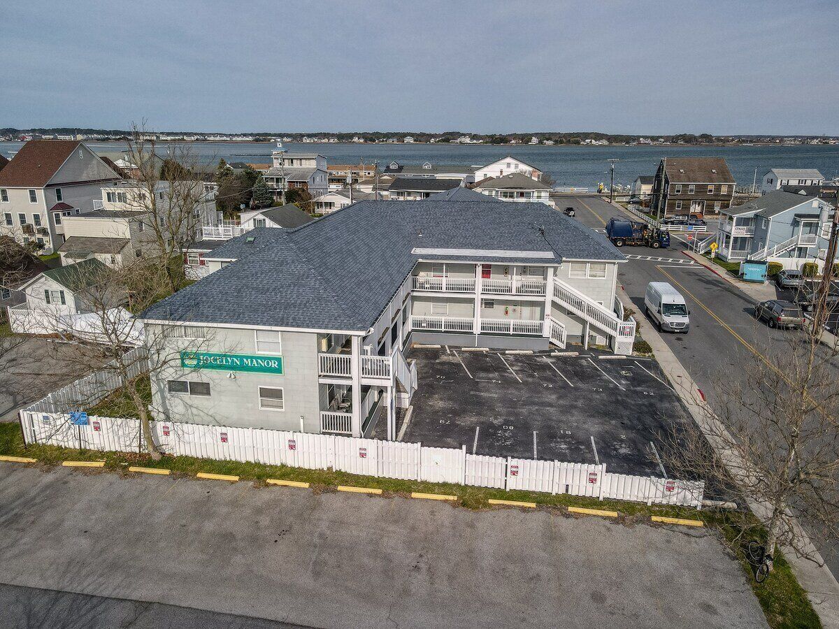 A motel with a parking lot, a covered area, and a view of the water.