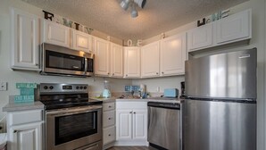 Una cocina moderna con armarios blancos, electrodomésticos de acero inoxidable y suelo de madera.