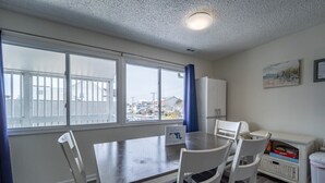 Un comedor con una mesa y sillas, una ventana con vistas, un armario y un cubo de basura.