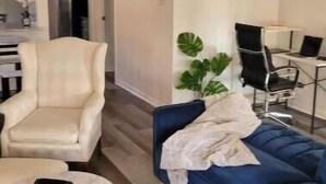 Una sala de estar moderna con un sofá azul, un sillón blanco y una mesita redonda.