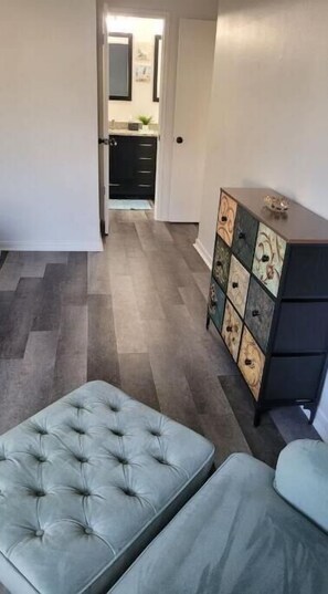 Relax in a spacious seating area with a tufted ottoman and stylish storage cabinet.