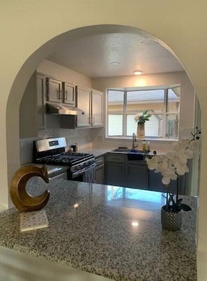 A kitchen with granite countertops, a stove, and a window with a view.