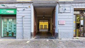 Eine Kopfsteinpflasterstraße führt zu einem Gebäude mit einer grünen Markise und einem Schild für eine Immobilienfirma.