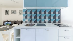 Une cuisine moderne avec un plan de travail blanc, deux éviers et un pare-feu orné de motifs géométriques.