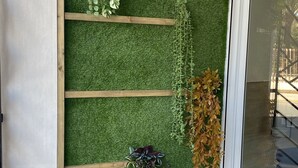 A wall with artificial grass and wooden shelves holding various plants. - New apartment in the center silver ground floor 2 rooms (Elche)
