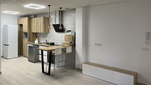 A modern kitchen with a built-in refrigerator, wooden cabinets, a bar area, and a white countertop. - New apartment in the center silver ground floor 2 rooms (Elche)