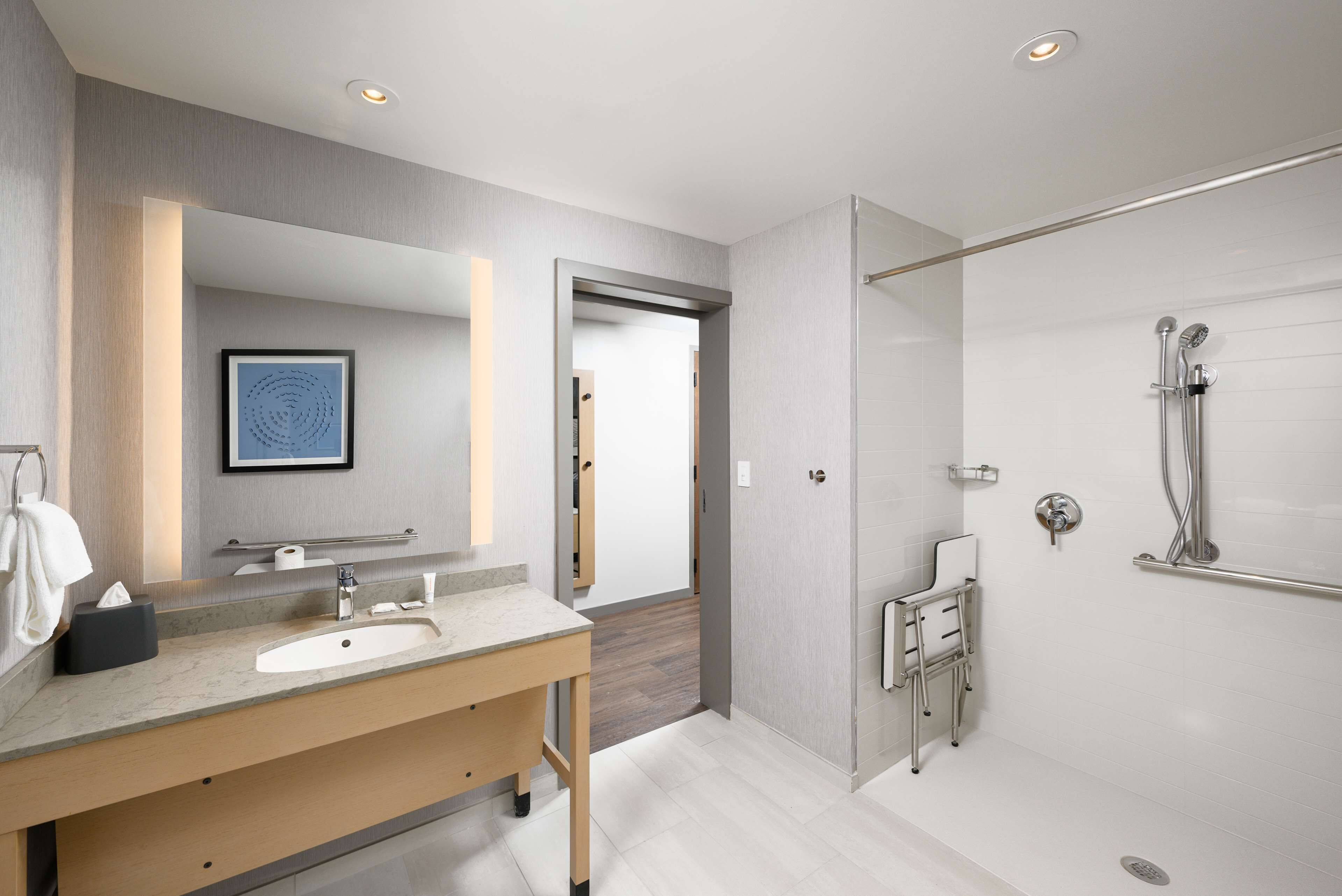 A modern bathroom with a sink, mirror, and shower.