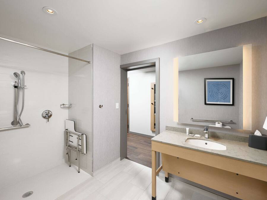 A modern bathroom with a walk-in shower, a vanity with a sink, and a large mirror.