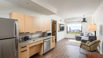 Una cocina moderna con armarios de madera, electrodomésticos de acero inoxidable y vistas a la ciudad a través de amplios ventanales.