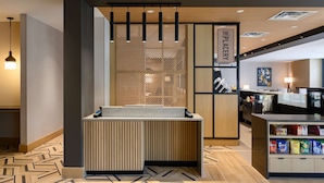 A modern reception area with a wooden reception desk, a counter with snacks, and a sign reading "The Plastery". - Hyatt Place Albany/Downtown (Albany)
