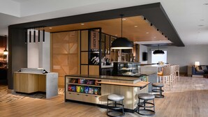 A modern bar area with a wooden counter, bar stools, and a variety of snacks. - Hyatt Place Albany/Downtown (Albany)