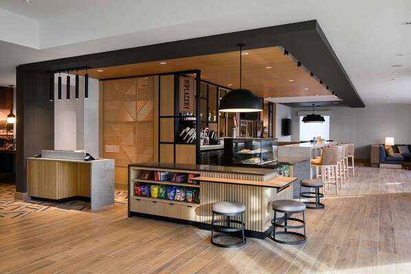 A modern bar area with a wooden counter, bar stools, and a variety of snacks.