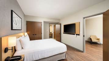 Habitació d'hotel amb un llit gran, una làmpada de nit, un telèfon i un televisor penjat a la paret.
