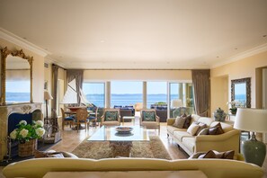 Un salon spacieux doté d’une grande fenêtre donnant sur la mer, et aménagé avec un canapé, des fauteuils et une table basse.