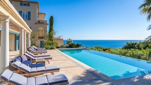 A poolside area with lounge chairs and a view of the ocean.
