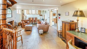 A spacious living area with a fireplace, leather sofas, wooden chairs, and a dining area with striped chairs. - Sympathetically stunning restored property. (Rickling Green, near Saffron Walden)