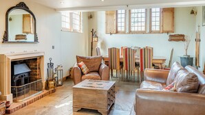 A spacious living room with a fireplace, leather sofas, a coffee table, and striped chairs. - Sympathetically stunning restored property. (Rickling Green, near Saffron Walden)