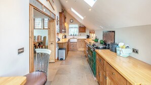 A kitchen with wooden cabinets, a dining area with a table and chairs, and a skylight above. - Sympathetically stunning restored property. (Rickling Green, near Saffron Walden)