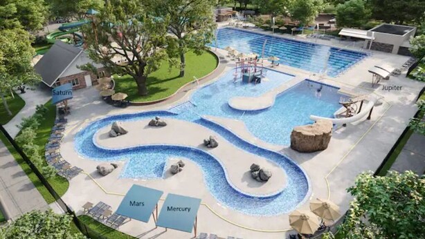 Una piscina con un elemento acuático serpenteante, zonas señalizadas con nombres de planetas y un pequeño edificio al fondo.