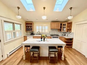 A kitchen with a central island, wooden cabinets, and a skylight.