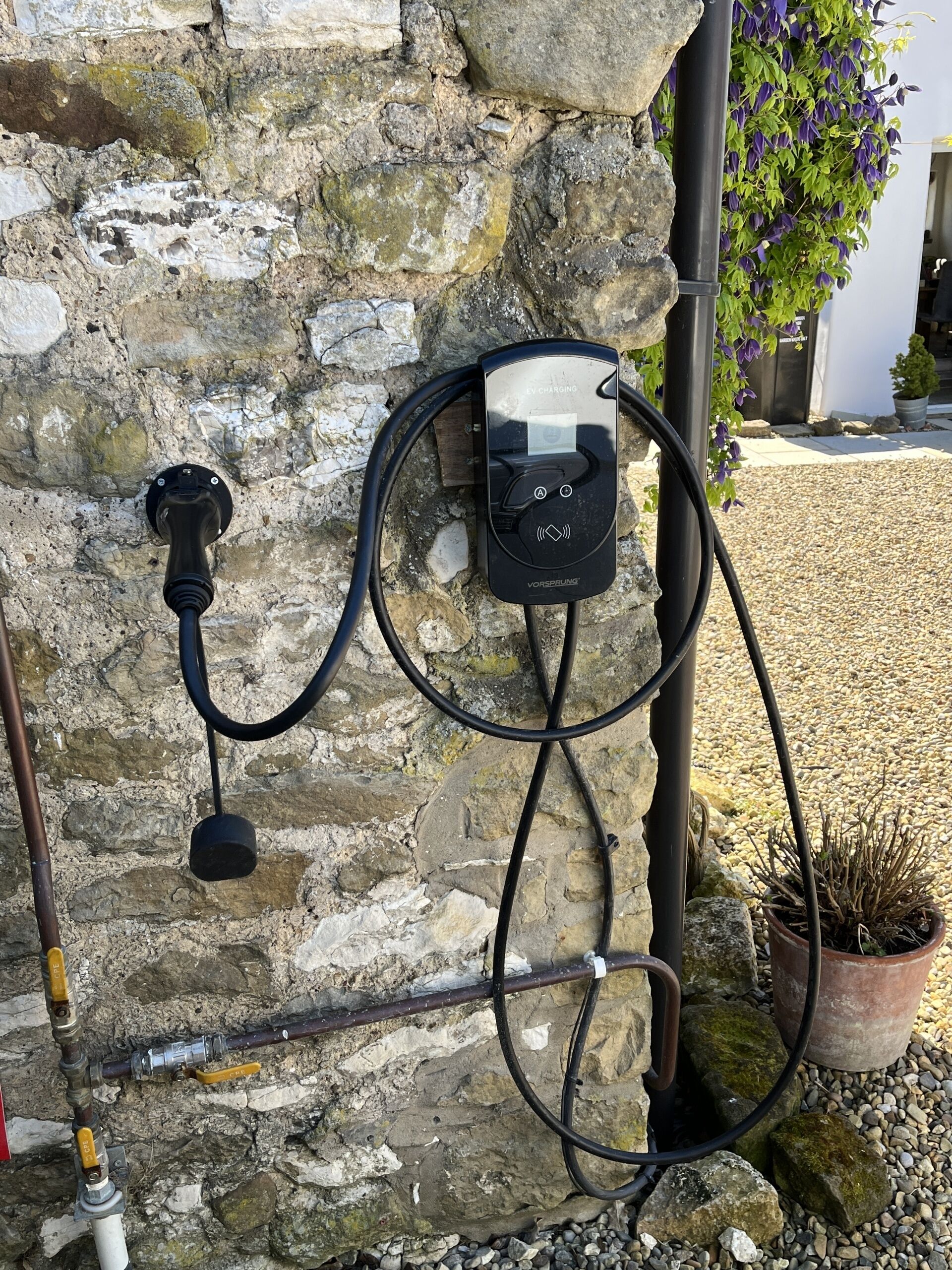 Una estación de carga para vehículos eléctricos fijada en una pared de piedra.