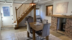 A dining area with a wooden table and chairs, a staircase, a brick fireplace, and a world map on the wall. - Blacksmiths Cottages (Filey)