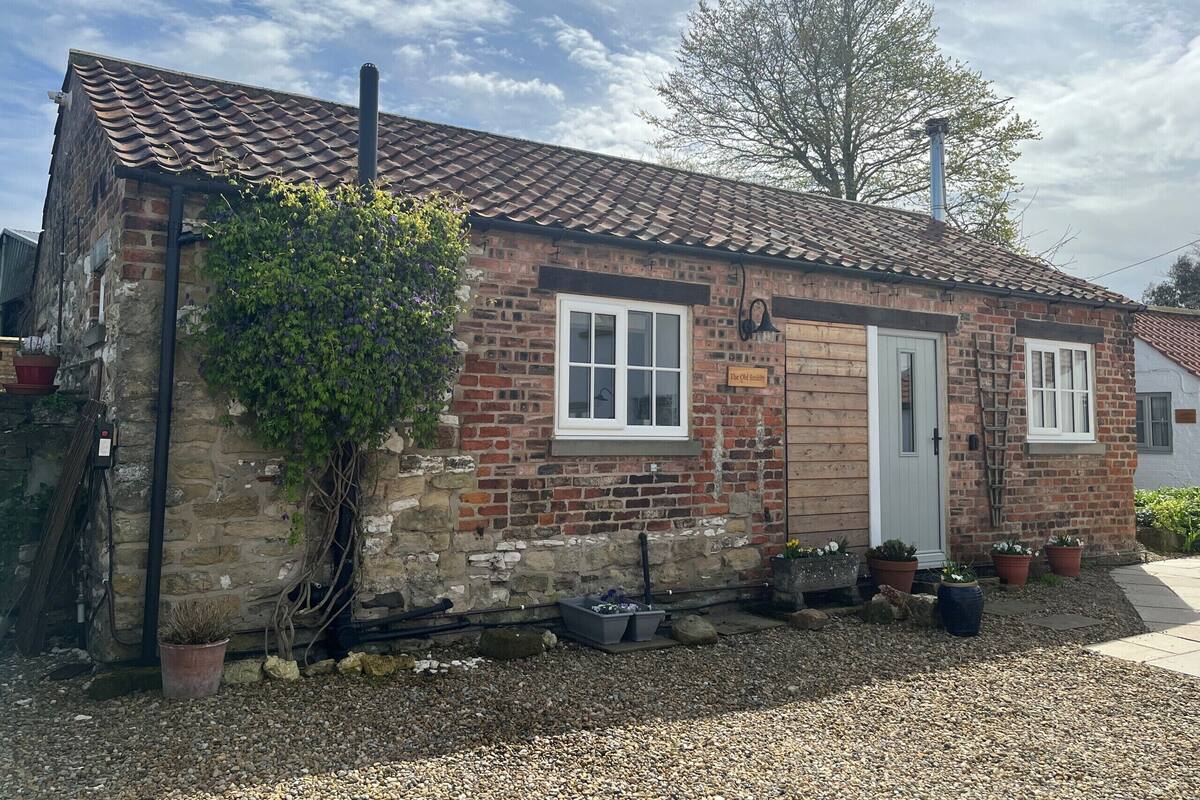 A small brick house with a tiled roof, a wooden door, and a window.