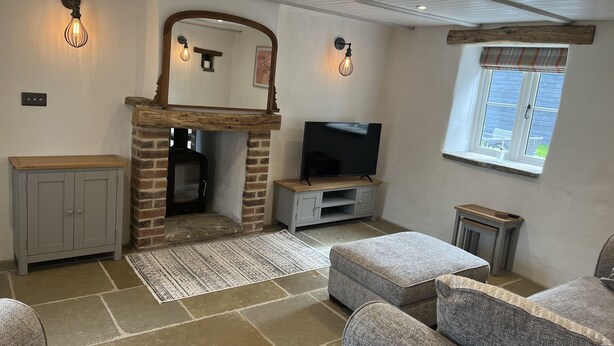 A cozy living room with a fireplace, a television, and comfortable seating. - Blacksmiths Cottages (Filey)