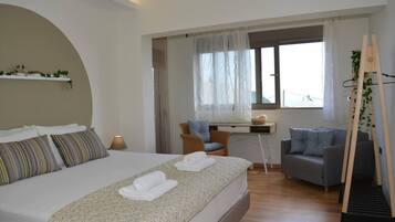 A modern bedroom with a large bed, a desk, and a chair.