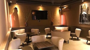 A lounge area with sofas and tables, a flat-screen TV mounted on the wall, and decorative wall art.