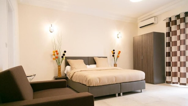 A bedroom with a bed, nightstands, a sofa, a wardrobe, and decorative vases.