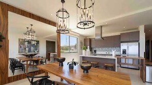 Een moderne keuken met een centraal eiland, hangende lampen en een uitzicht op de stadshemel.