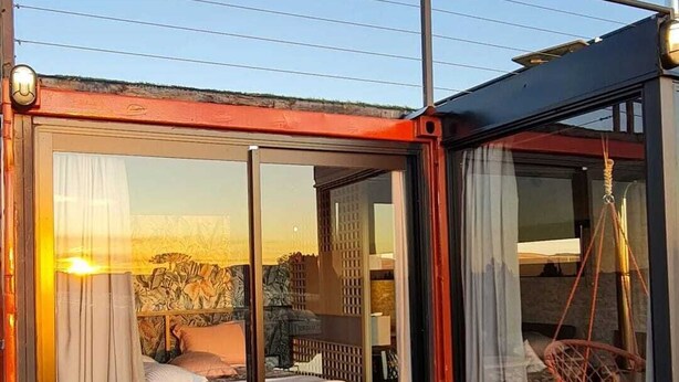 Une chambre dotée d’une grande porte-fenêtre coulissante, d’une terrasse en bois et offrant une vue sur le paysage.