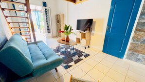 A living room with a blue sofa, a patterned chair, a TV, and a blue door. - Zandoli, swimming pool, sea view, peaceful, garden (Sainte-Luce)