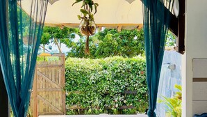A poolside area with a wooden bench, a small table with drinks, and a hanging plant. - Zandoli, swimming pool, sea view, peaceful, garden (Sainte-Luce)
