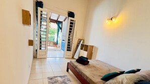 A bedroom with a bed, a nightstand, a lamp, and a view of the outside balcony. - Zandoli, swimming pool, sea view, peaceful, garden (Sainte-Luce)