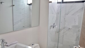 Ein Badezimmer mit Waschbecken, Spiegel und Toilette, sowie einer Duschkabine.