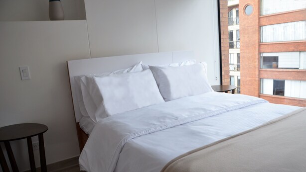 Ein ordentlich bezogenes Bett mit weißen Leinen in einem Hotelzimmer.