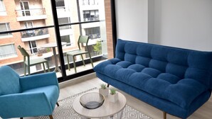 Ein modernes Wohnzimmer mit einem blauen Sofa, einem blauen Sessel und einem runden Couchtisch mit einem geometrischen Teppich.