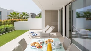 A modern outdoor dining area with a table set for breakfast, including croissants, fruit, and a glass of orange juice. - Contemporary modern apartment [119] (Lagos)