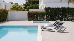 Una piscina con sillas de descanso, rodeada de vegetación y arquitectura moderna.